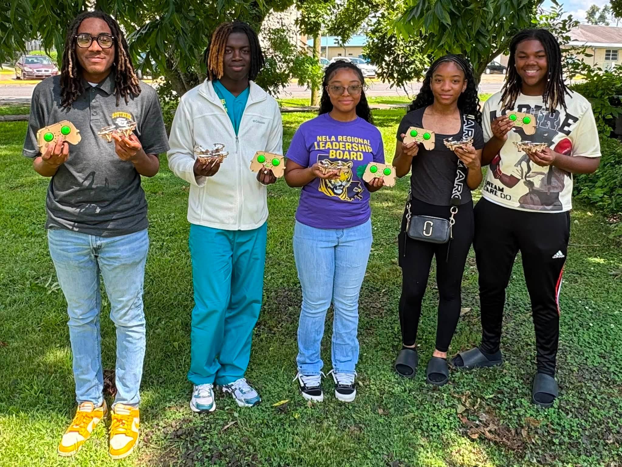 A man with a group of teenagers holding small drones.